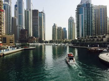 Boats in canal amidst buildings in city against sky