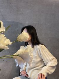 Flowers by woman sitting against wall