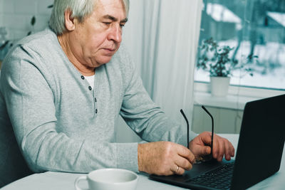 Senior man using laptop at table