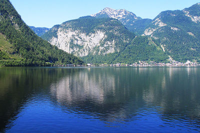 Scenic view of lake and mountains against clear blue sky