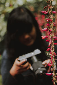 Close-up of woman looking at camera by flowering plant