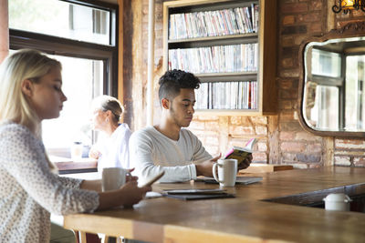 People resting while having coffee at bar counter in cafe