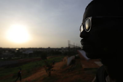 Portrait of man looking away against sky during sunset