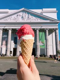 Person holding ice cream against built structure