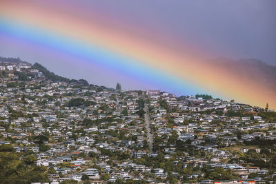 Rainbow over illuminated buildings in city against sky