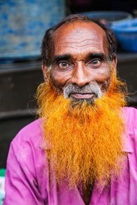 Portrait of senior man with dyed beard sitting outdoors