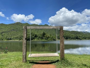 Wooden posts on field by lake against sky