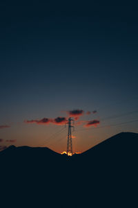 Low angle view silhouette of electricity pylon against sky during sunset