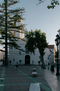 Street amidst trees and buildings against sky