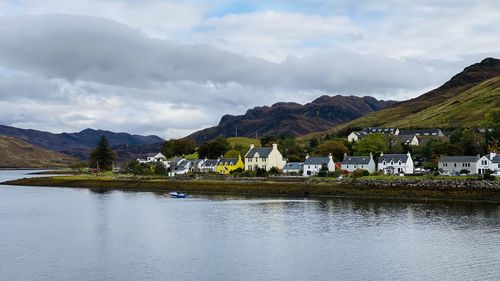 Houses by lake against sky