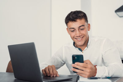 Young man using phone while sitting on table