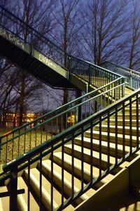 Staircase by illuminated city against sky at night