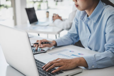 Midsection of businesswoman using laptop at office