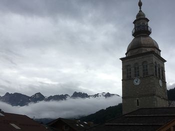 Low angle view of clock tower against cloudy sky