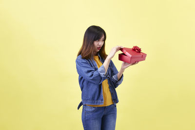 Full length of woman standing against yellow background