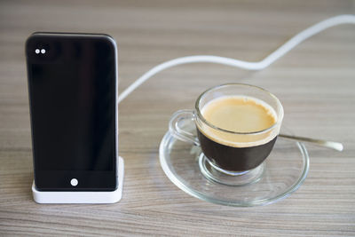 Close-up of coffee cup by smart phone on table