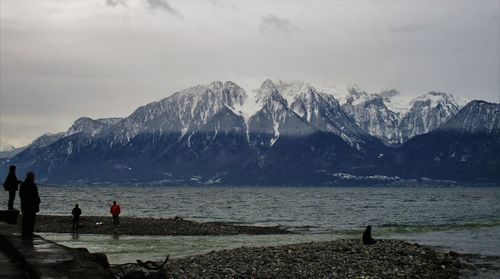 Scenic view of snowcapped mountains in front of river on sunny day