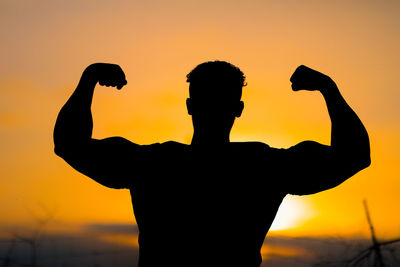 Silhouette man standing against orange sky during sunset