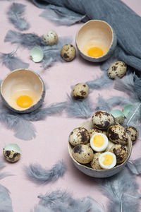 Quail eggs in ceramic vases, gray feathers on the table, easter still life,