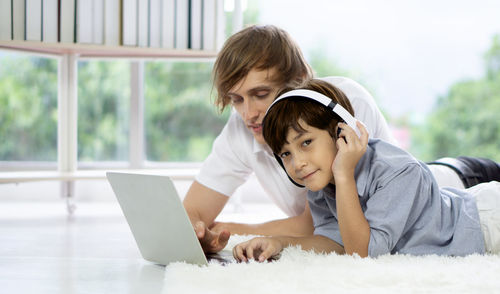 Rear view of siblings sitting on laptop
