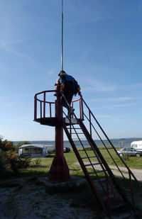 Lifeguard hut on land by sea against sky