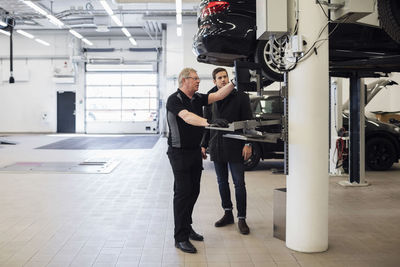 Senior mechanic explaining customer while standing at repair shop