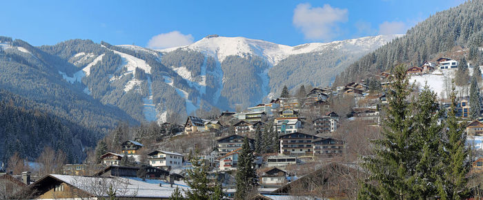 Panoramic view of tourist village on sunny slope of austria alps under blue winter sky
