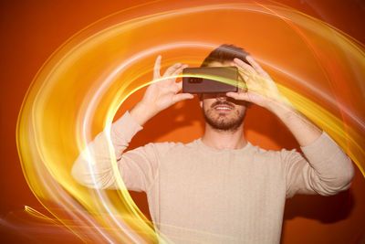 Young man taking photo smartphone on a orange colored background