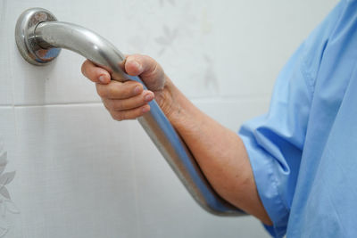 Midsection of person holding handle in bathroom