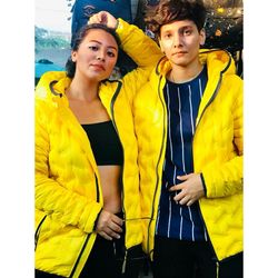 Portrait of young couple standing against yellow