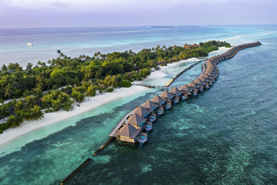 Maldives, lhaviyani atoll, kuredu, aerial view of row of coastal bungalows at dawn