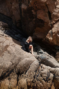 Rear view of woman sitting on rock