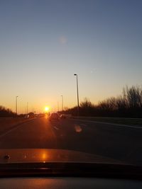 Cars on road against sky during sunset