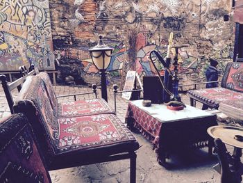 Hookah on table by empty chairs against graffiti on wall