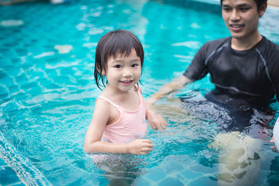High angle portrait of happy girl with father in swimming pool