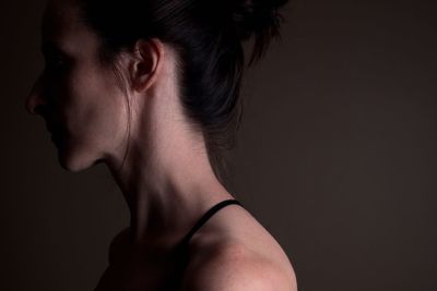 Close-up of young woman against black background