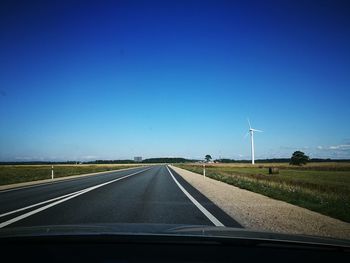 Country road against blue sky seen through car windshield