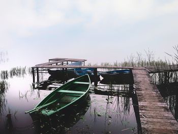 Fishing boat moored at pier against sky