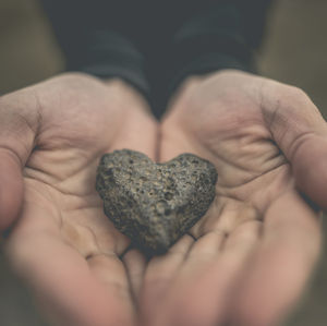 Cropped hands of person holding heart shape rock