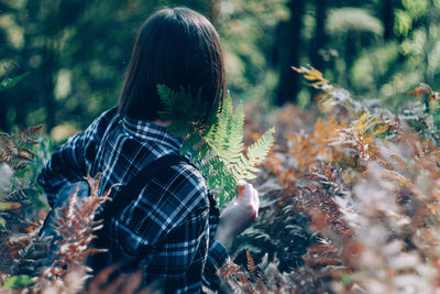 Rear view of man standing by tree in forest