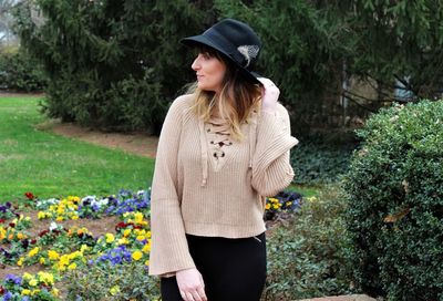 Young woman looking away while standing by plants at park