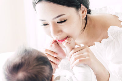 Close-up of smiling mother playing with son on bed at home