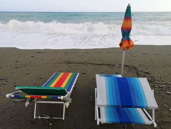 Chairs on beach against sky