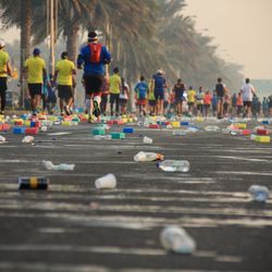 Bottles on street against people running in marathon