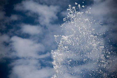 Close-up of spraying water against clouds