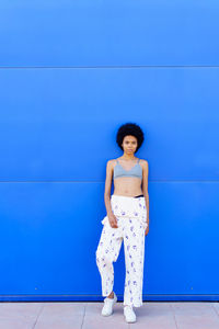 Young woman standing against blue wall