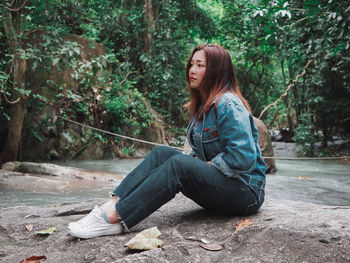 Woman sitting at lakeshore in forest