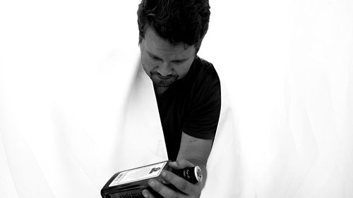 Close-up of man holding smart phone against white background