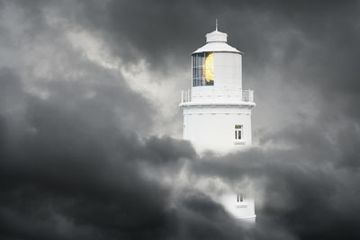 Low angle view of lighthouse by building against sky
