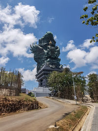 Statue of road against cloudy sky